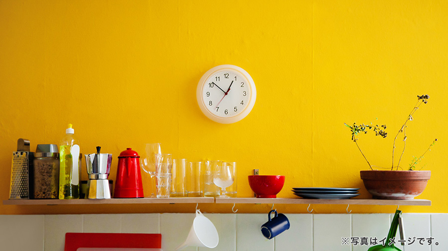 キッチンの黄色い壁にかかる掛け時計