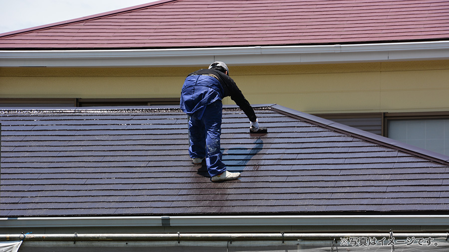 屋根に登り塗装をする職人