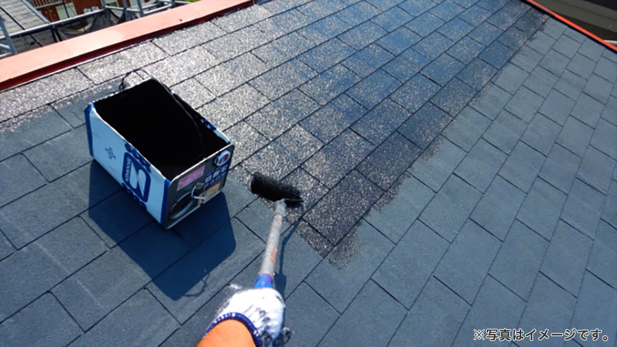 スレート屋根を塗装する作業員