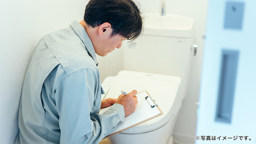 トイレのチェックをする作業服の男性