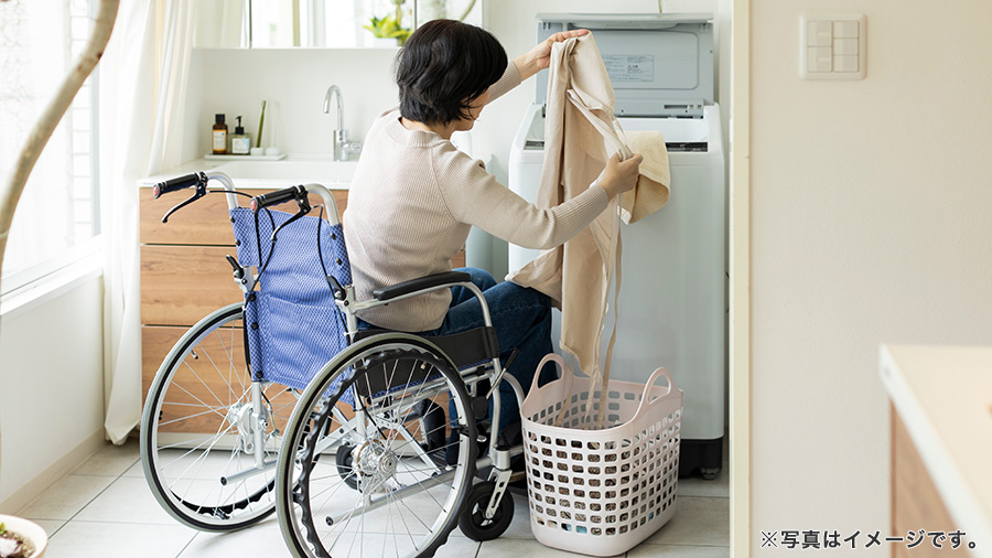 車椅子で洗濯する女性